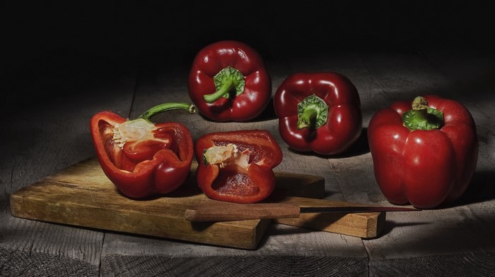 Red bell peppers on a cutting board with a knife