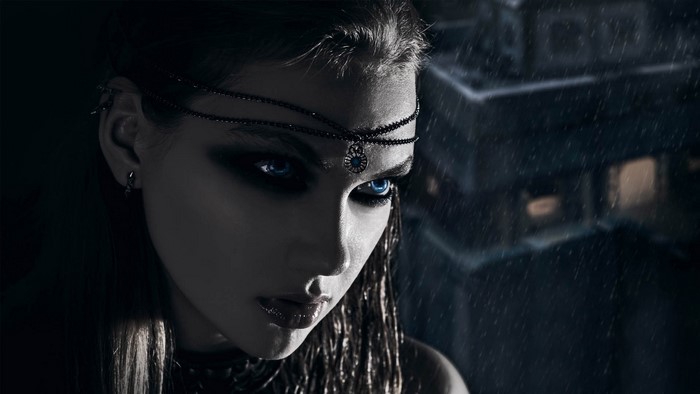Woman with blue eyes and dark makeup in the rain
