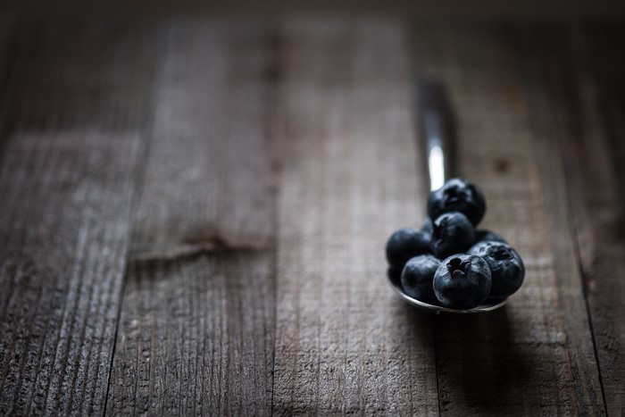 Blueberries on a spoon on a wooden surface