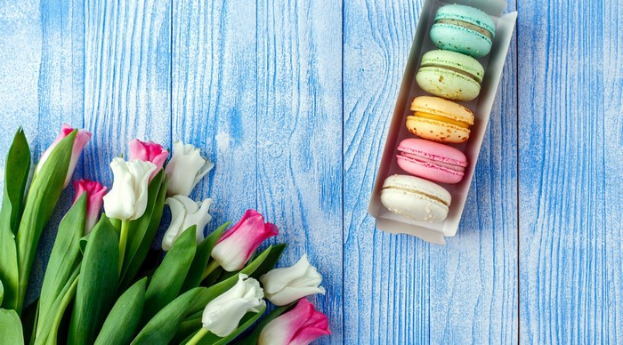 Colorful macarons and tulips on a blue wooden surface