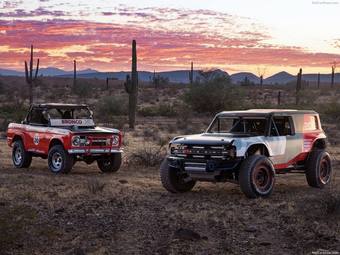 Two Ford Broncos in a desert at sunset