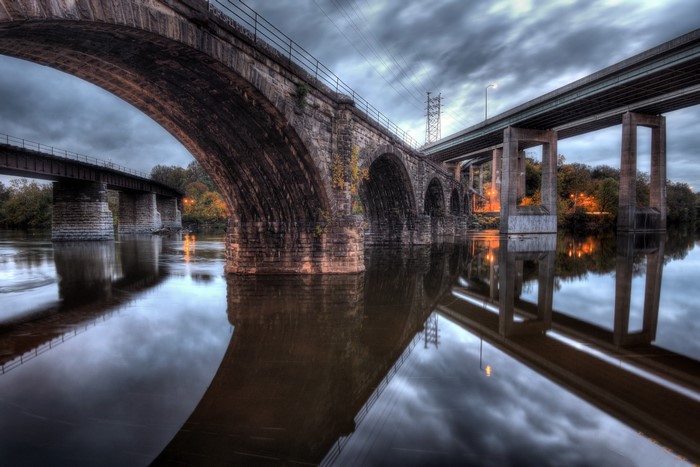 Stone and concrete bridges over a river at dusk