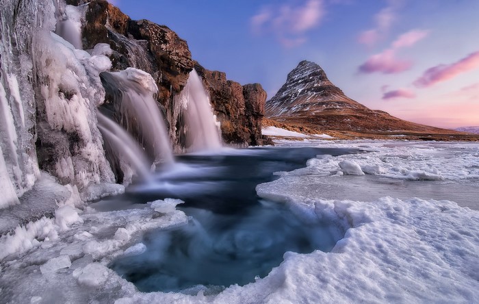 Frozen waterfall and Kirkjufell mountain in Iceland