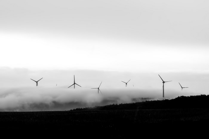 Wind turbines emerging from mist in a monochrome landscape