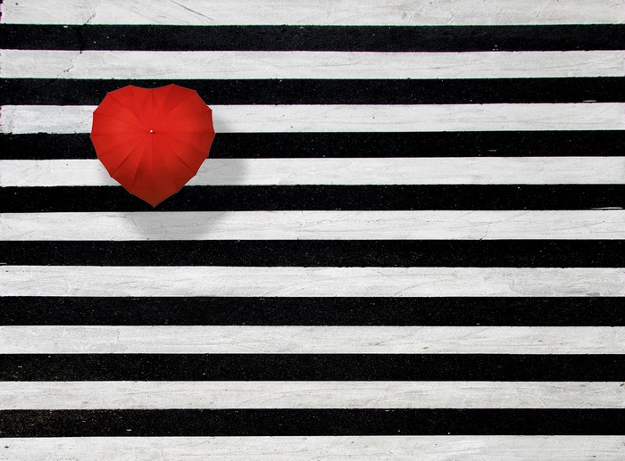 Red heart-shaped umbrella on black and white stripes