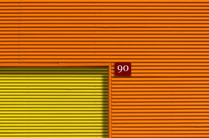 Orange and yellow corrugated metal wall with number 90