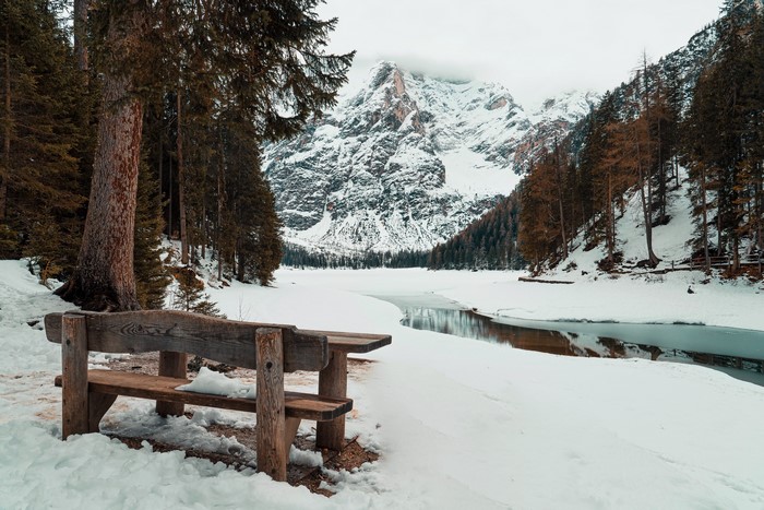 Wooden bench in front of a snowy mountain landscape