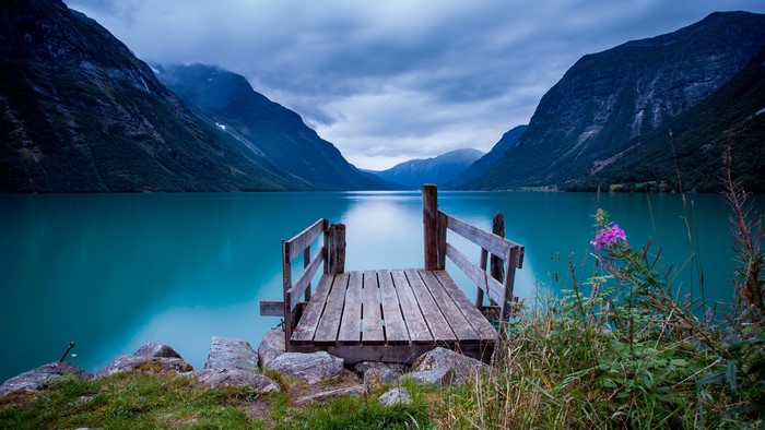 Wooden dock on a turquoise lake surrounded by mountains