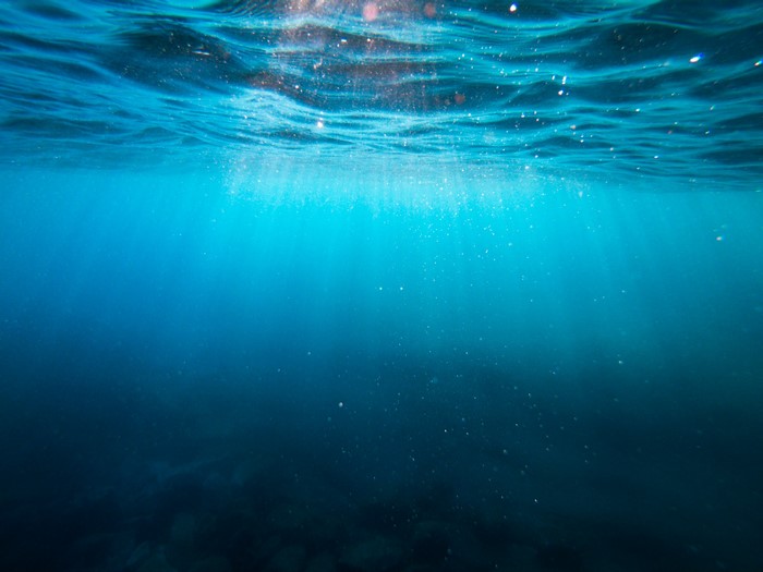 Underwater view with sun rays in blue water