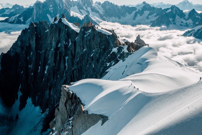 Hikers on a snowy mountain ridge in the Alps