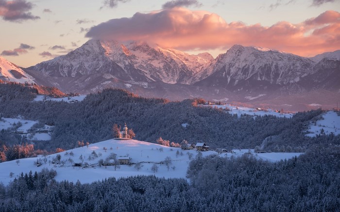 Snowy mountains and hills with a church in Slovenia