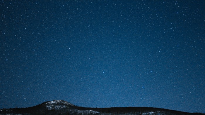 Night sky full of stars over a snowy landscape