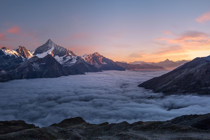 Mountain range above clouds at sunset