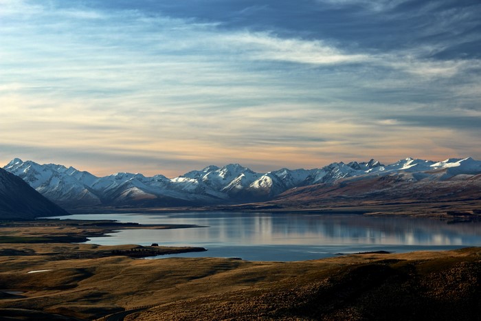 Snow-capped mountains reflected in a calm lake at sunset