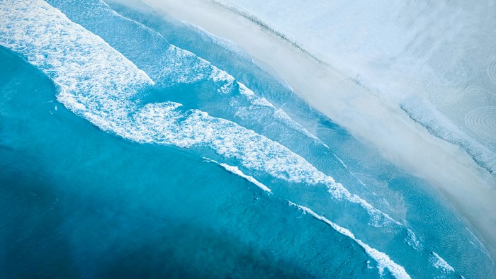 Top view of ocean waves crashing on a sandy beach