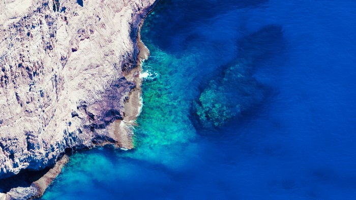 Aerial view of rocky coastline and clear blue ocean