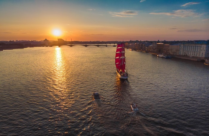 Sailboat with red sails on a river at sunset in St. Petersburg