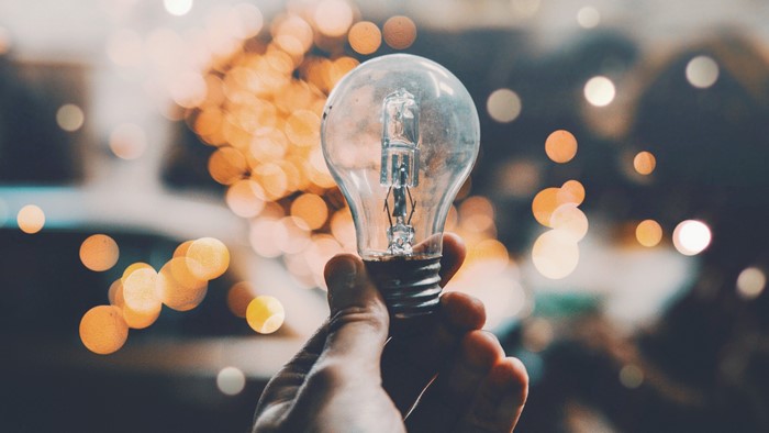 Hand holding a light bulb with bokeh lights