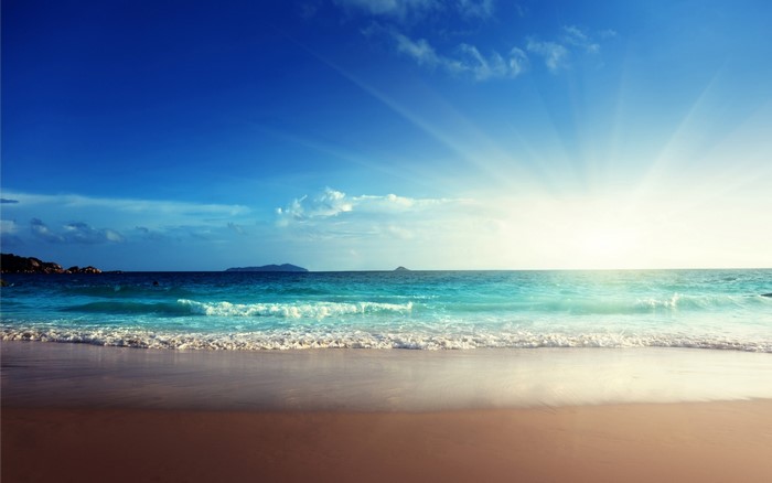 Beach with ocean waves and sun rays