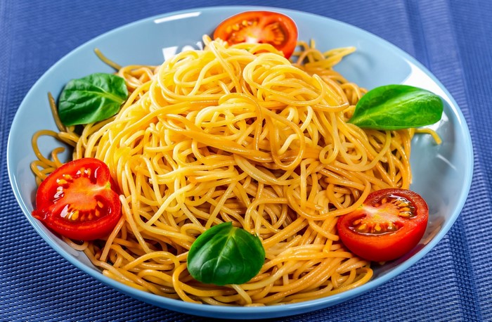 Spaghetti with tomatoes and basil on a blue plate