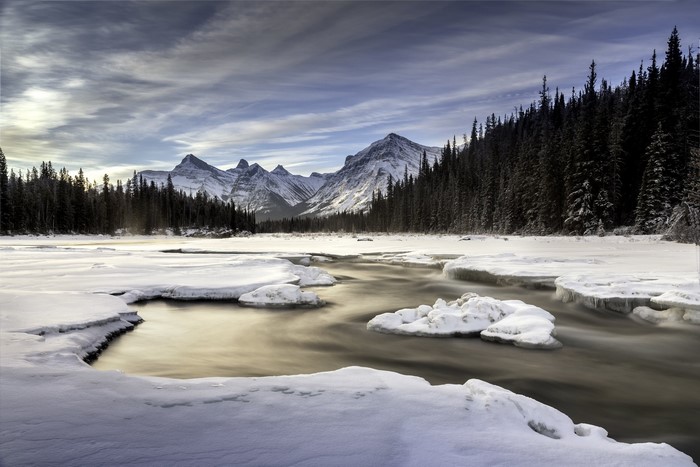 Winter landscape with mountains, forest, and river in Canada