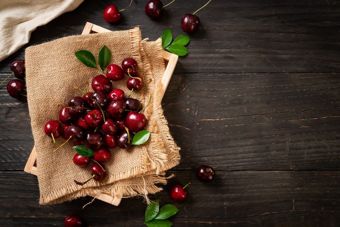 Cherries on a burlap cloth on a wooden surface