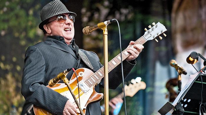 Van Morrison performs on stage with a guitar