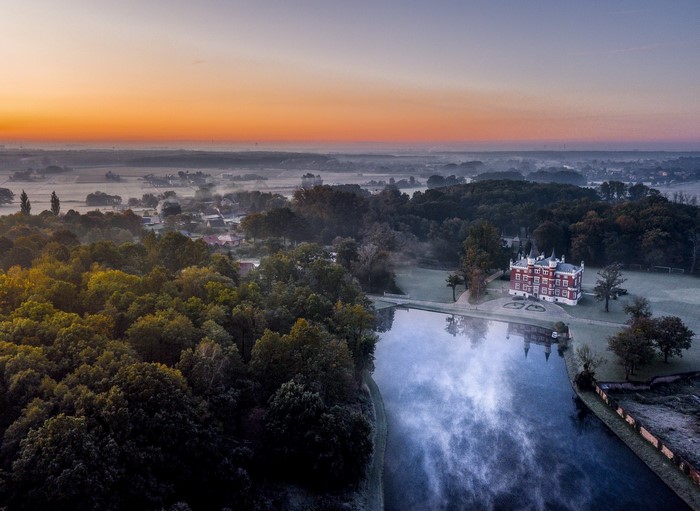 Aerial view of a castle and lake at sunrise in Poland