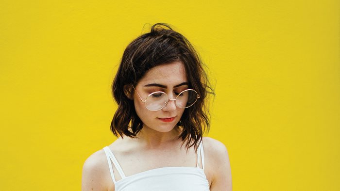 Dodie with glasses against a yellow background