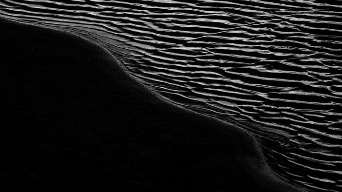 Monochrome abstract of sand ripples and dark water