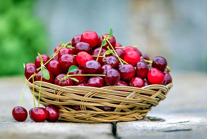 Basket of fresh cherries on a wooden surface
