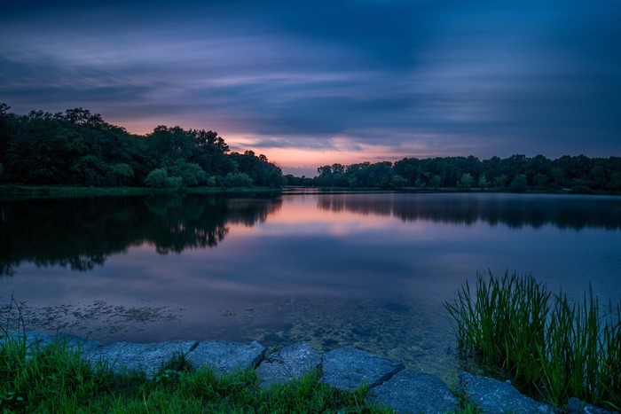 Sunset over a calm lake with trees and rocks