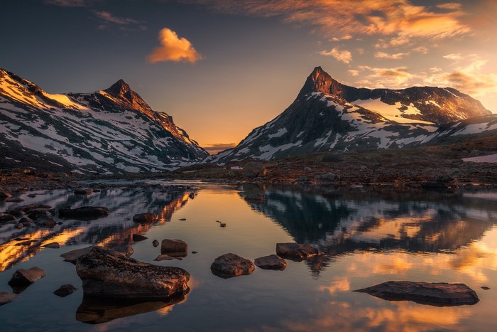 Snow-capped mountains reflecting in a lake at sunset