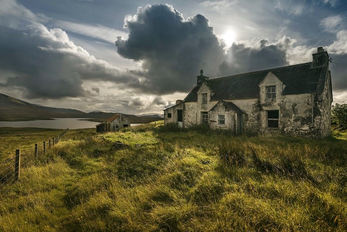 Abandoned house on a hill with a lake and stormy sky