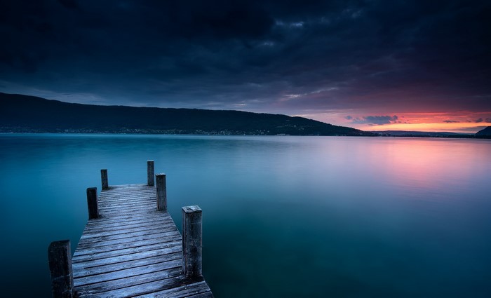 Wooden pier on a lake at sunset with dark clouds