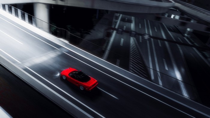 Red convertible sports car on a highway at night