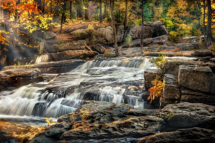 Waterfall flowing over rocks in an autumn forest