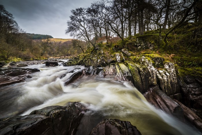 River flowing over rocks with trees on the bank