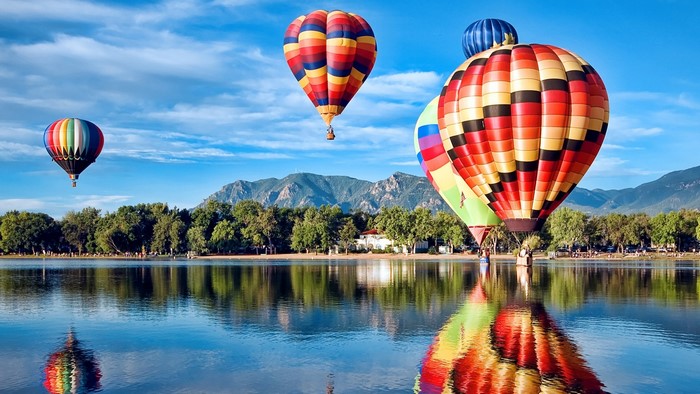 Hot air balloons over a lake with mountains