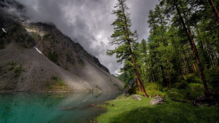 Turquoise lake at the foot of a rocky mountain with a forest