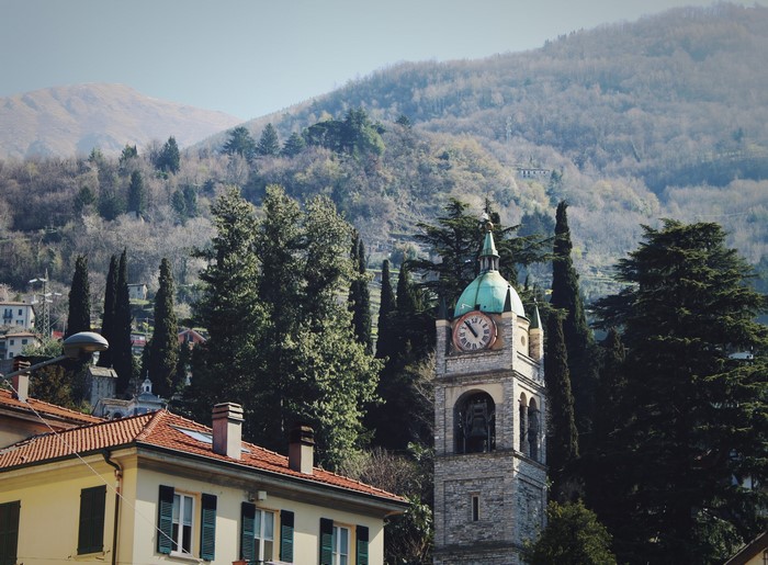 Bell tower with clock in a mountainous Italian landscape