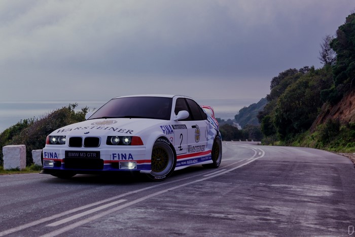 BMW M3 GTR FINA Warsteiner race car on a coastal road