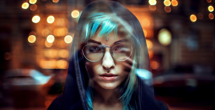 Woman with blue hair and glasses wearing a hoodie