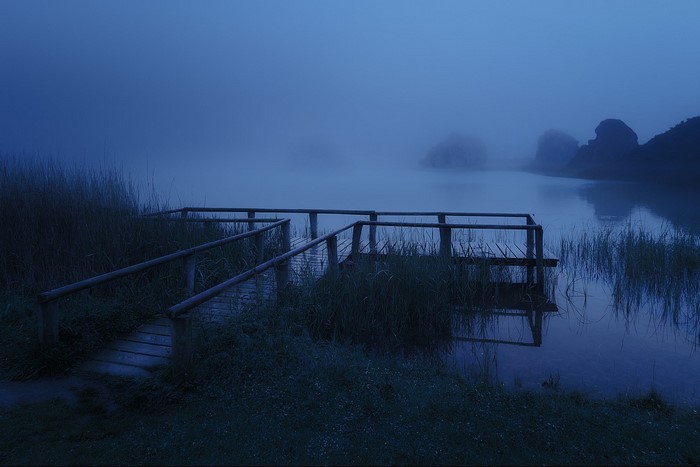 Wooden pier on a misty lake at dusk