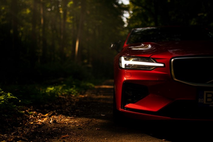 Red Volvo S60 with LED headlight in forest