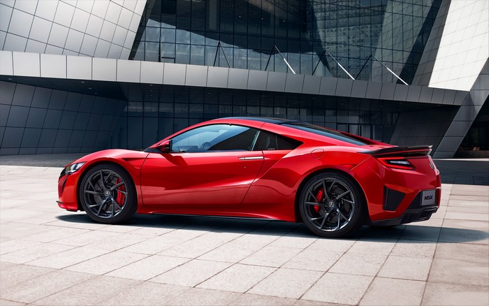 Red Acura NSX sports car parked in front of modern architecture