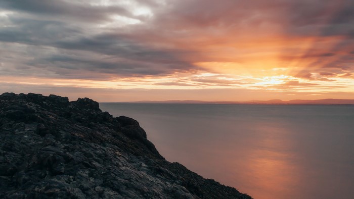 Rocky cliff overlooking the ocean at sunset