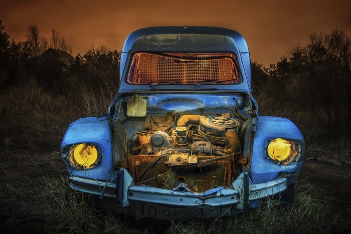 Blue car wreck with open hood at night