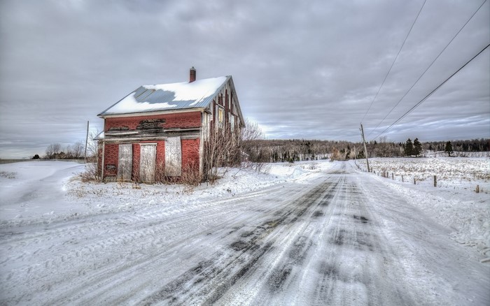 Abandoned brick house in winter by a snowy road