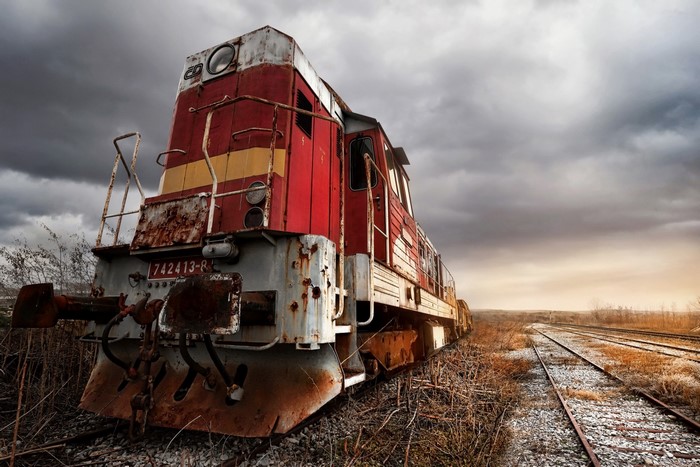 Abandoned red and white locomotive on train tracks